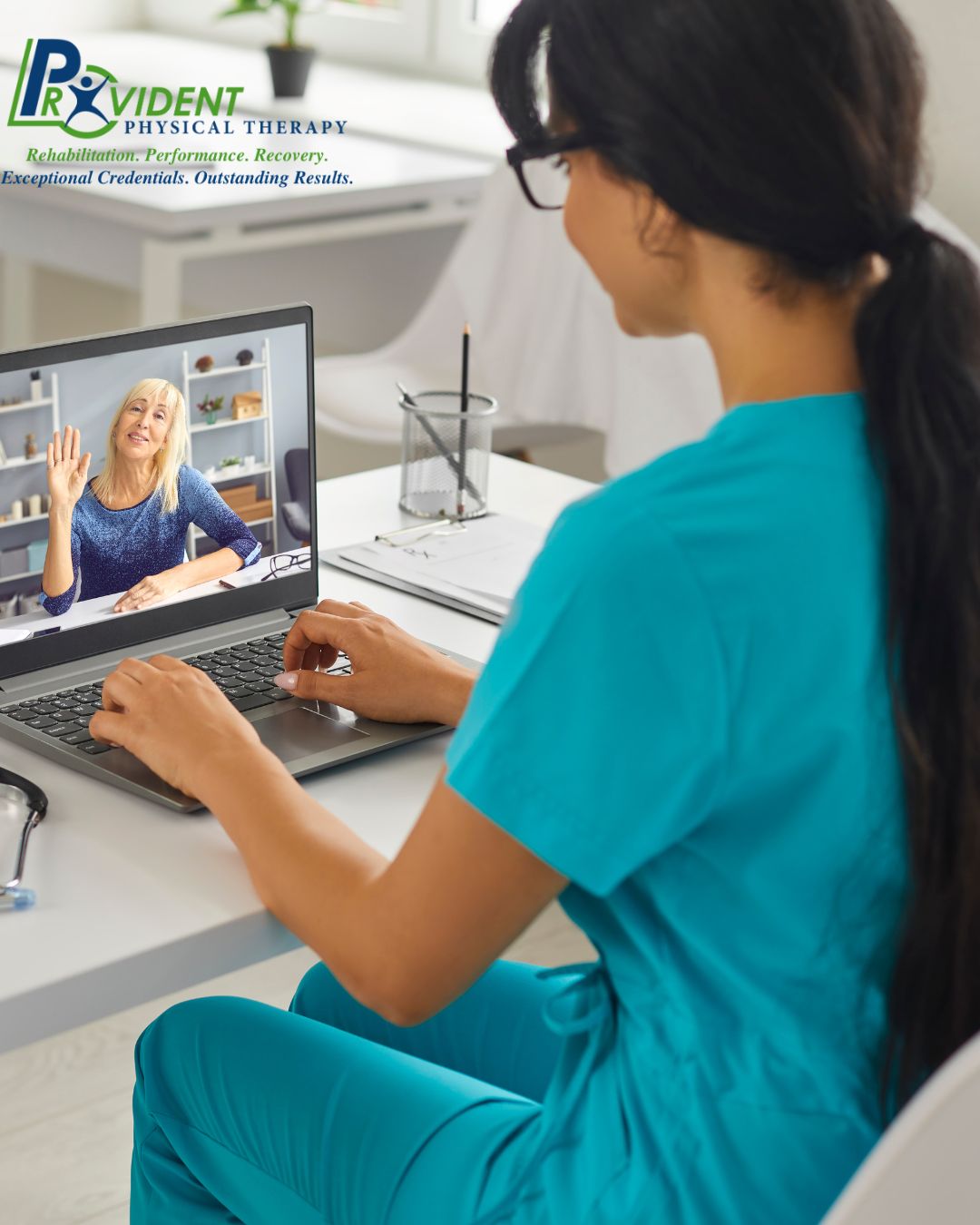 A healthcare professional in blue scrubs has a video call with a patient on a laptop at a desk in an office, showcasing Telehealth Physical Therapy in New York State  The Provident Physical Therapy logo is visible in the upper left corner 