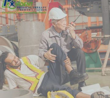 A worker sits on the floor holding his leg in pain while another worker in a hard hat speaks into a walkie talkie at an industrial site 